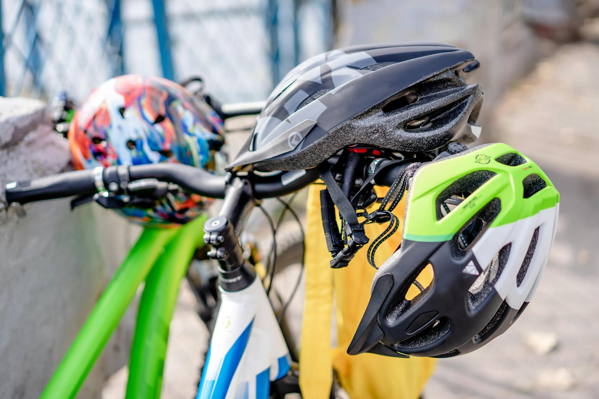 Close-up of brightly colored bicycle helmets resting on bike handlebars, emphasizing safety.